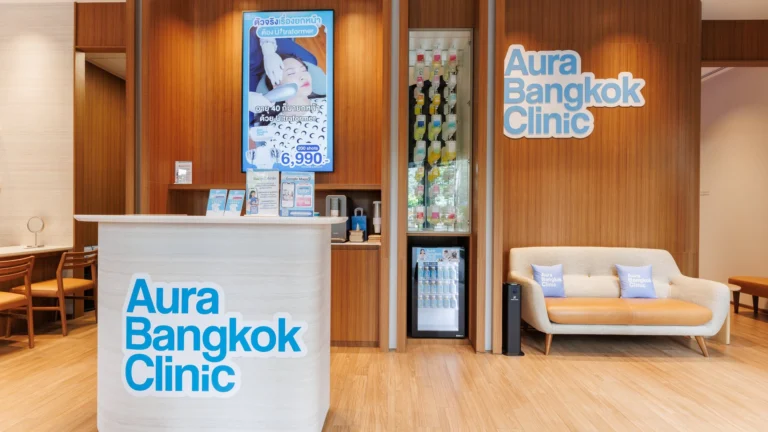 Reception of the Aura Bangkok Clinic Sathorn branch with branded desk and lounge sofa