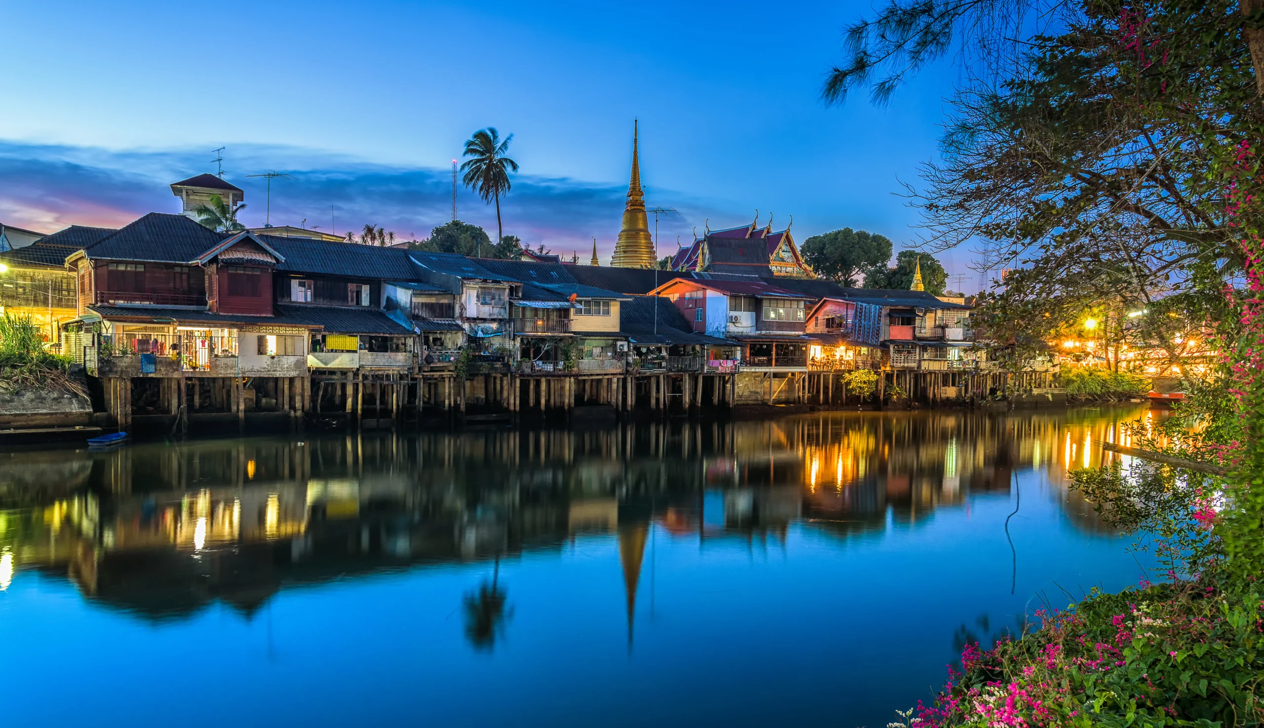 Old riverside houses of the Chanthaboon Waterfront reflected in the river at dusk, Chanthaburi