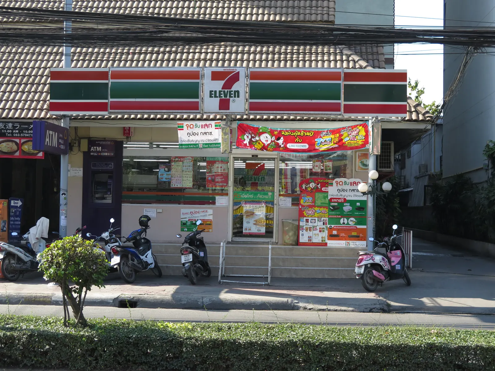 A 7-Eleven storefront in Chiang Mai with scooters parked outside and an ATM — where most of a Thailand packing list can be bought