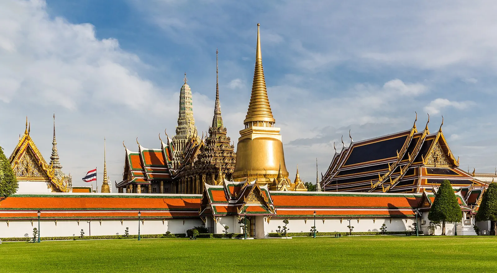 The golden chedi and spires of Wat Phra Kaew rising above the Grand Palace walls, seen from Sanam Luang