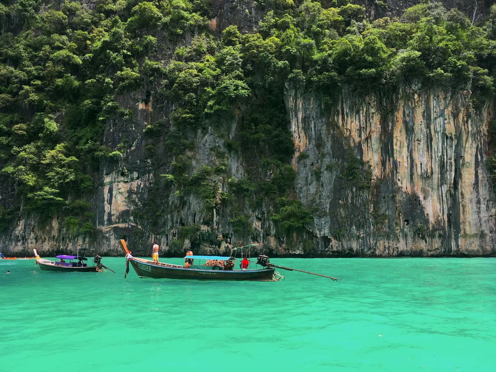 Longtail boat in the green water of Pileh Lagoon under the cliffs of Phi Phi Leh