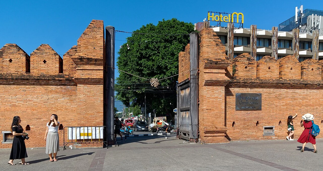 Tha Phae Gate in Chiang Mai, the restored brick gate and city wall on a clear day, with tourists on the plaza