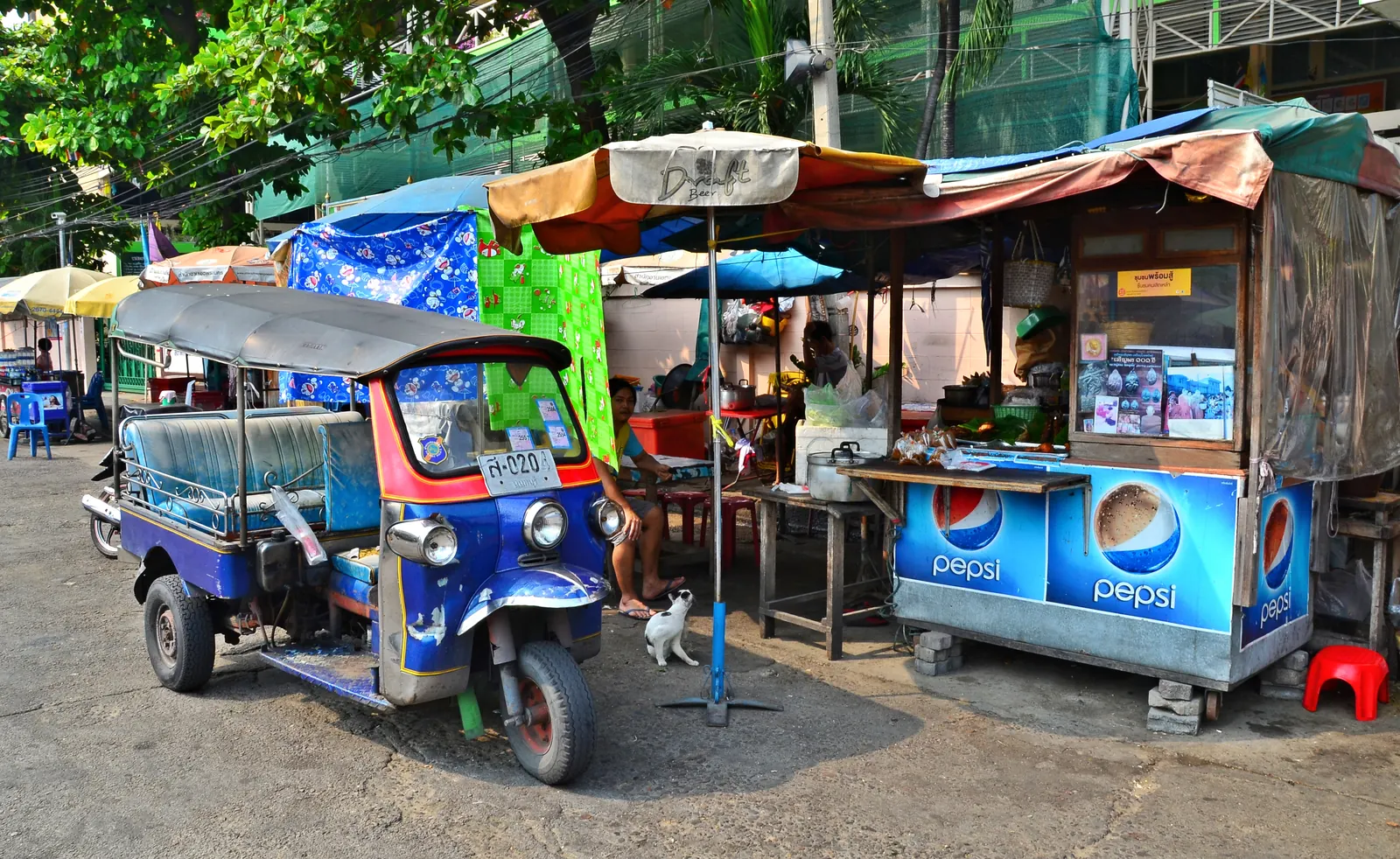 Tuk-tuks parked beside a street food stall in Bangkok