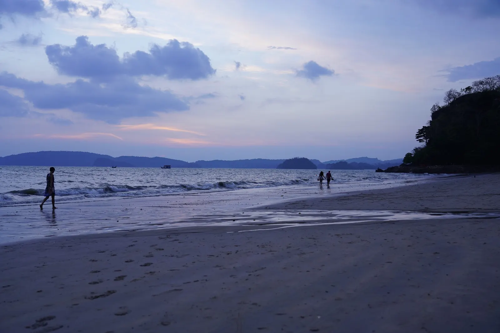 Longtail boats lined up on Ao Nang beach in Krabi province with limestone cliffs behind
