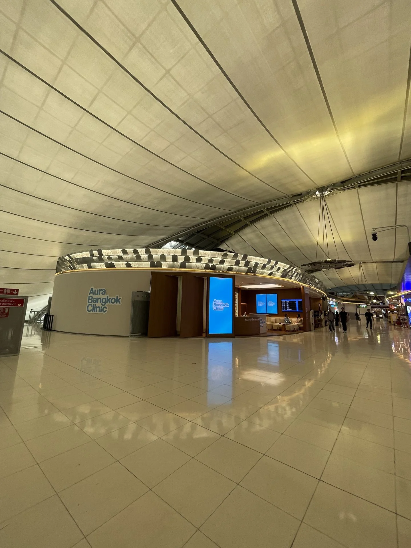 Aura Bangkok Clinic Suvarnabhumi Airport branch seen across the international departure hall under the terminal roof