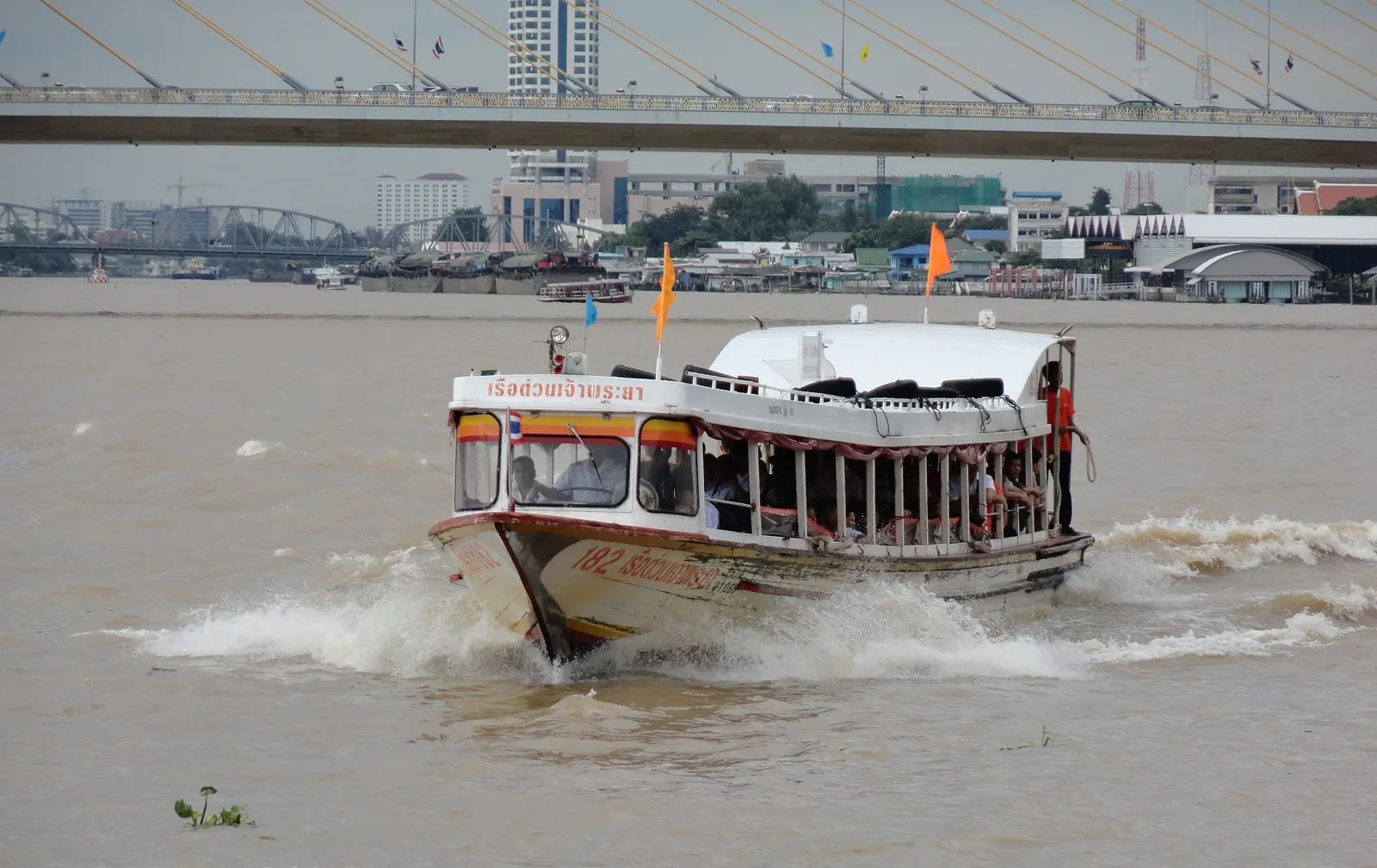 An orange-flag Chao Phraya Express boat on the river in Bangkok