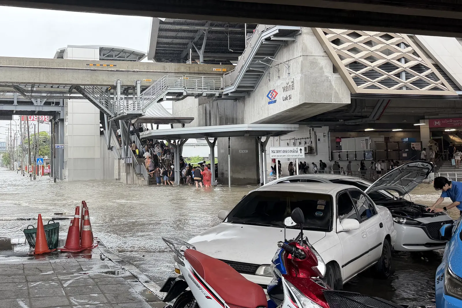 Commuters wading through flooded walkways beneath the elevated rail station at Lak Si, Bangkok, on 27 September 2026