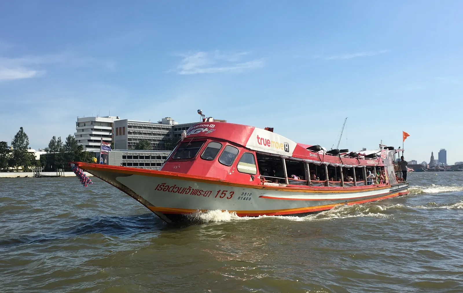 An orange-flag Chao Phraya Express Boat on the river in Bangkok