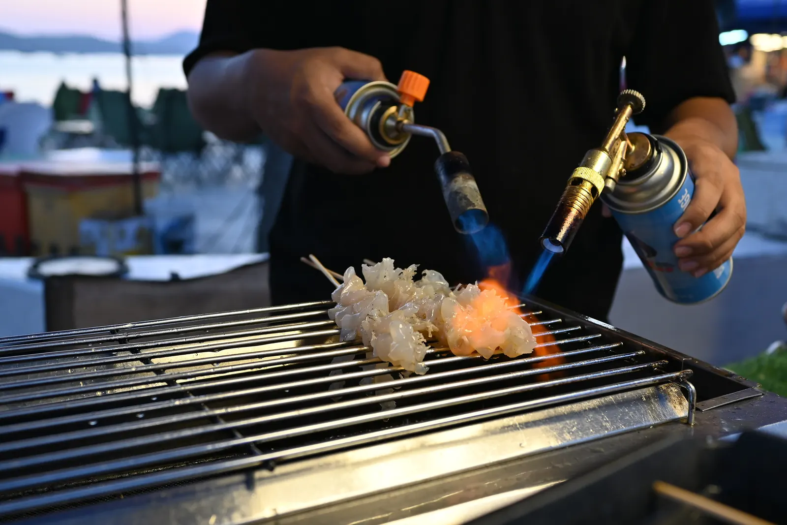 Seafood skewers searing on a Thai night-market grill