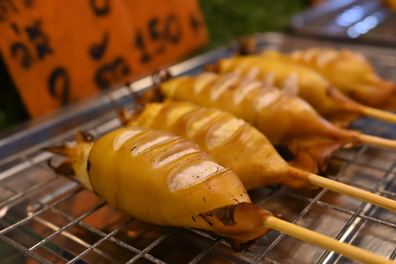 Grilled squid skewers charring over charcoal at a Thai night-market stall