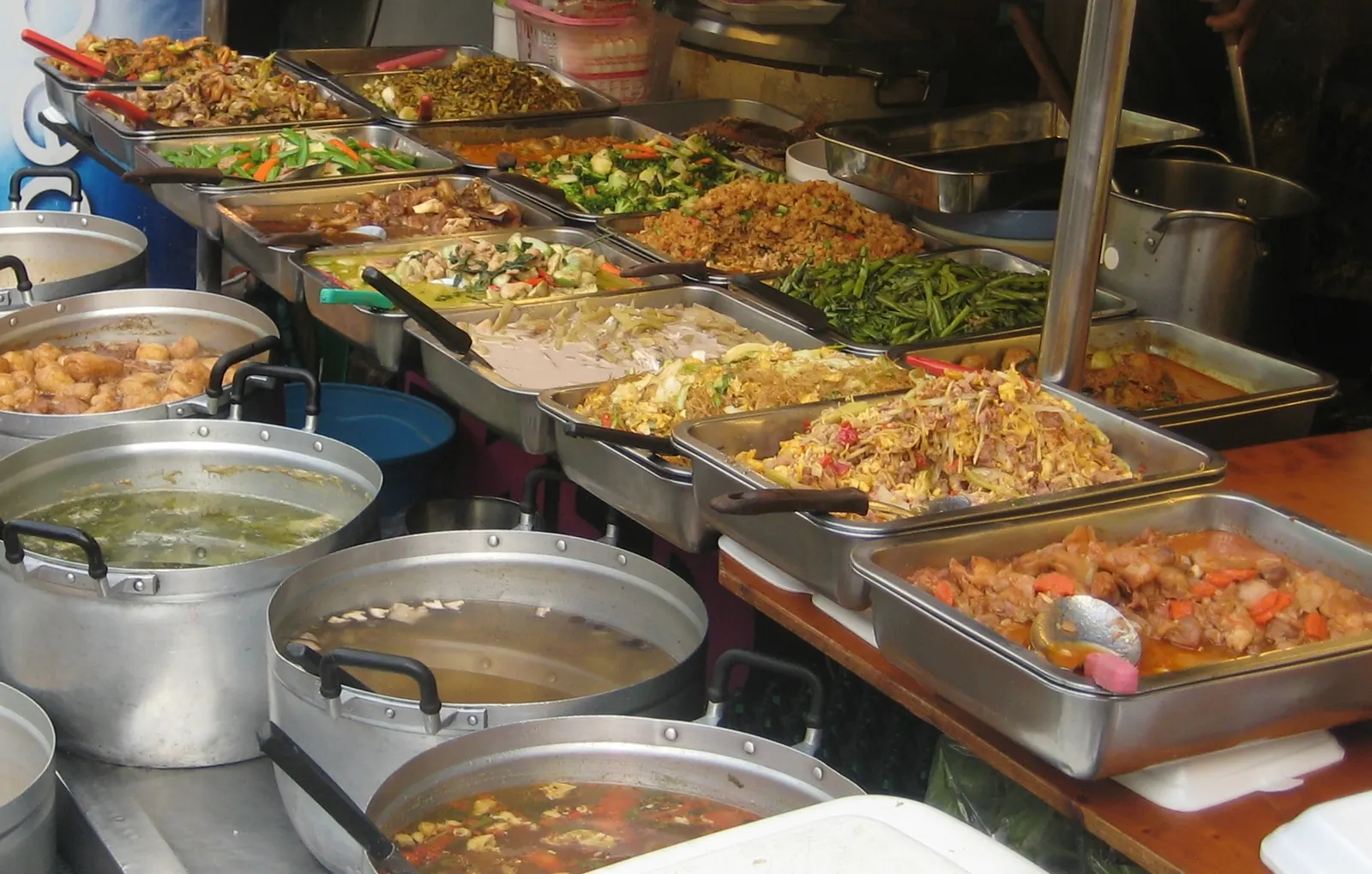 Trays of cooked curries and stir-fries at a street food stall in Bangkok's Chinatown