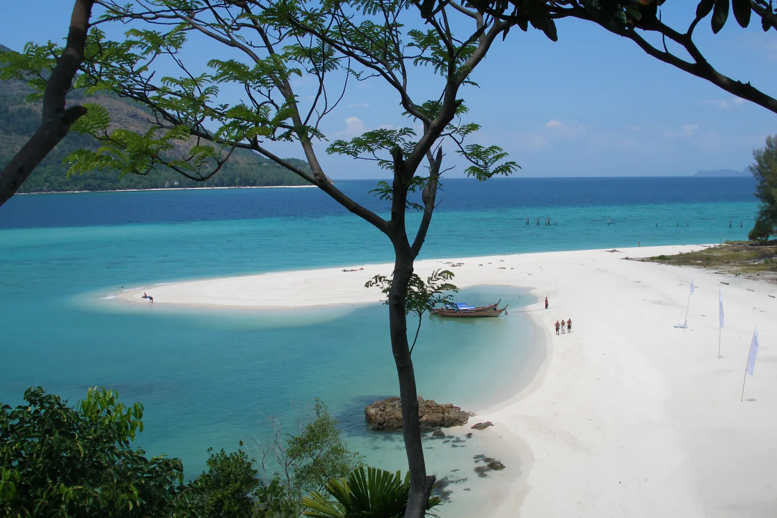 A white sand spit and turquoise shallows on Koh Lipe with longtail boats pulled up on the sand