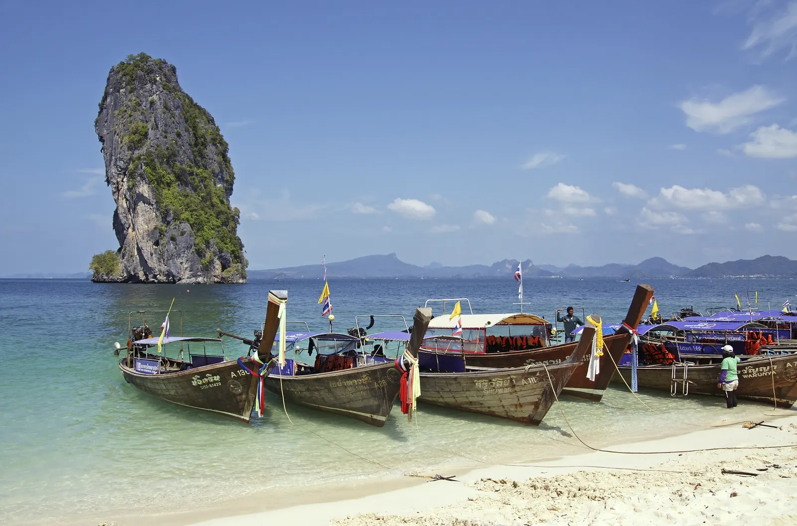 Longtail boats moored off Koh Poda with Krabi's limestone cliffs behind, on the Four Islands tour