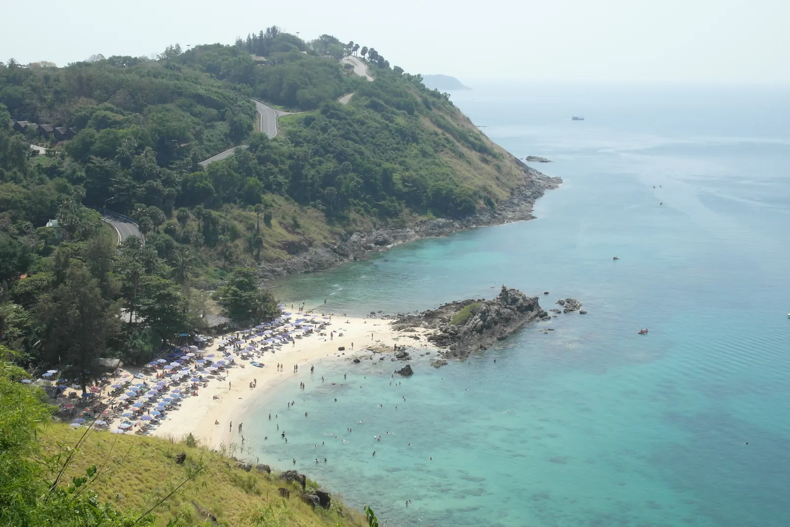 Nai Harn Beach in southern Phuket, a wide bay of pale sand between two green headlands