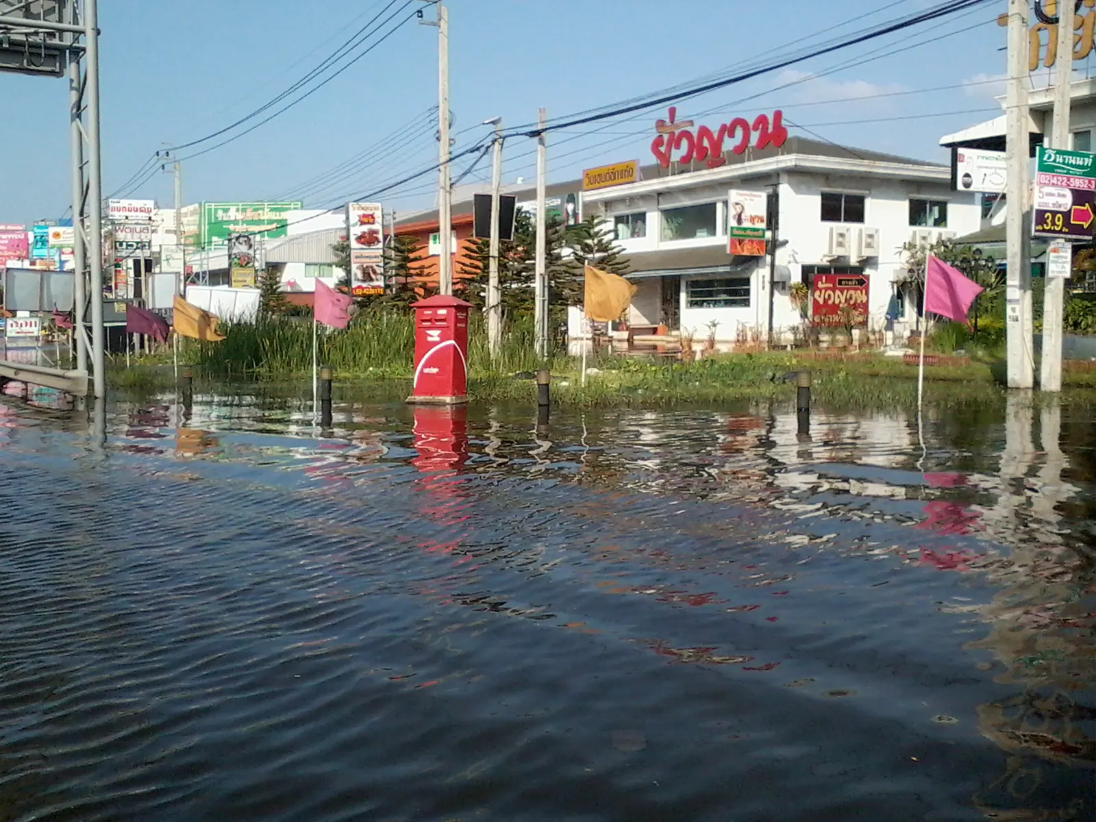 A flooded street in Bangkok with vehicles driving through standing water