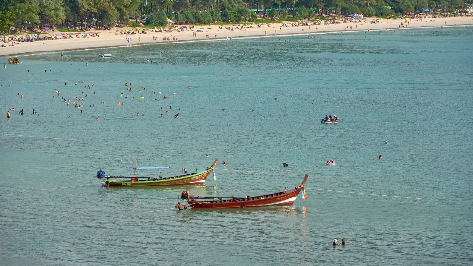 Kata Beach, Phuket, in the high season with longtail boats and swimmers