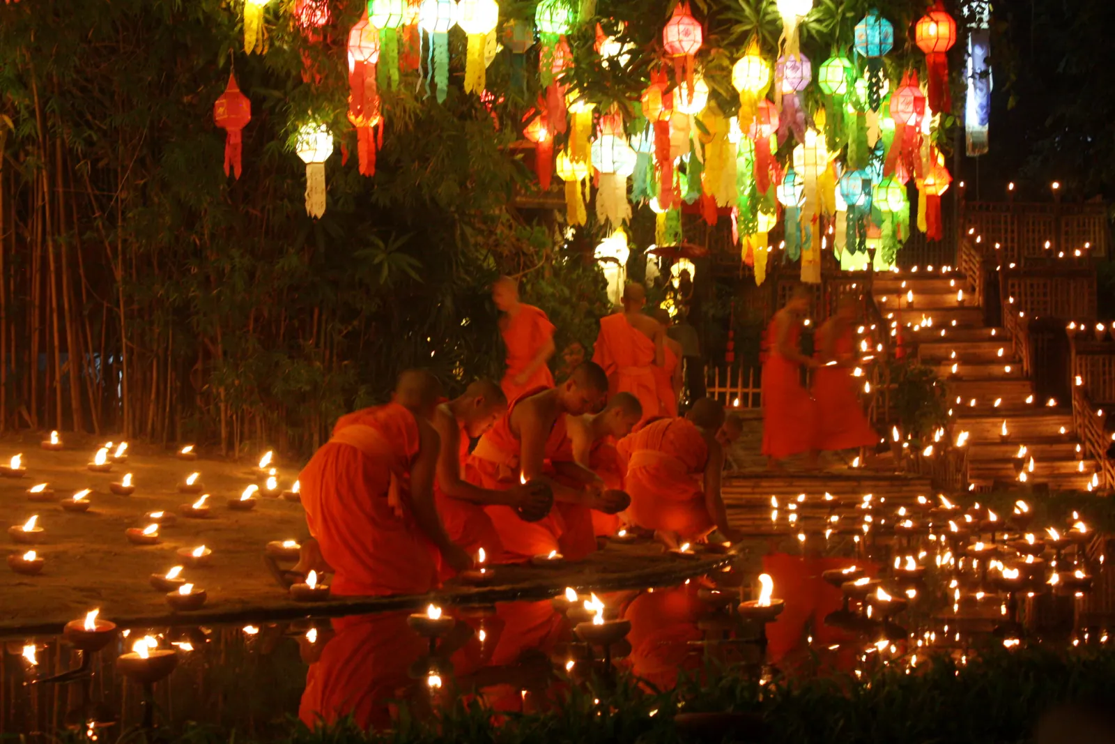Monks lighting candles and krathongs at Loy Krathong in Chiang Mai, with lanterns overhead